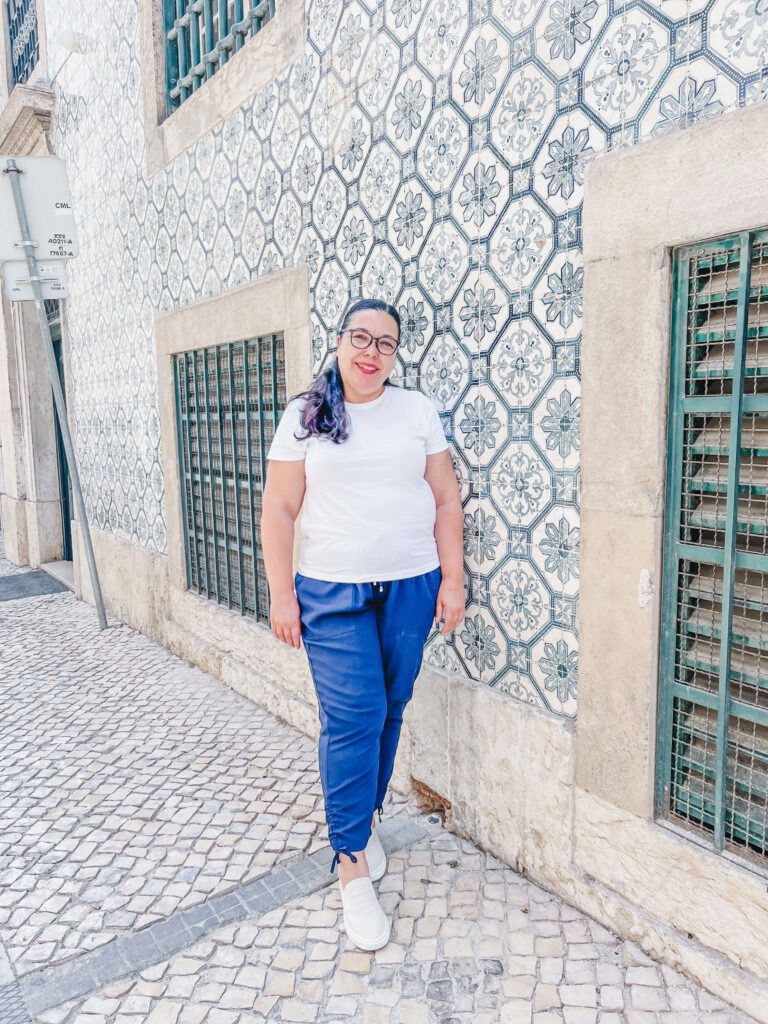 Isabel in Lisbon against a green tiled building